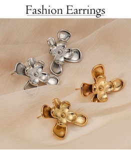 Gros plan de boucles d'oreilles fleurs dorées et argentées sur tissu en soie beige