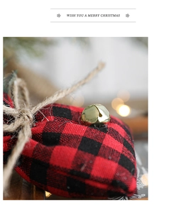 Close-up of red and black plaid heart ornament with a small golden bell and jute rope handle