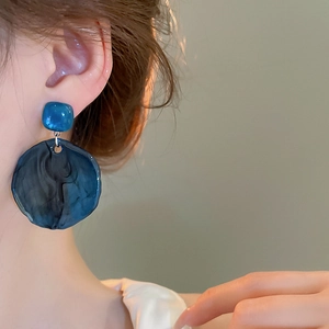 Close-up of model wearing blue marble resin hoop earrings with square stud detailing