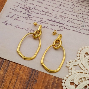 Detailed shot of golden oval titanium steel earrings on vintage letter paper with lace