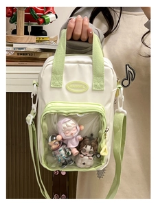 Detail of cream and green crossbody ita bag with clear PVC window showing plush toys