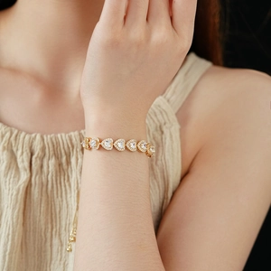 Detail of adjustable gold double heart bracelet with pavé-set zircons on female wrist