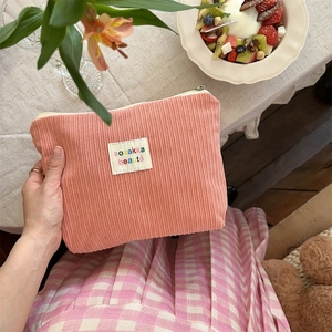 Pink corduroy makeup bag with sozakka beaute label held in a lifestyle setting