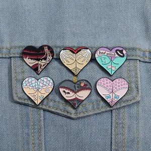 Detailed view of heart-shaped enamel pins with gothic motifs on denim jacket