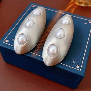 Détail des boucles d'oreilles ovales en argent brossé avec trois perles incrustées