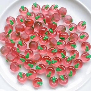 Macro shot of 3D mini red resin apples scattered on a white plate for DIY crafts
