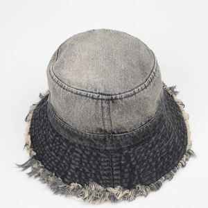 Détail d'un chapeau bob en jean délavé avec bords effilochés et design bicolore gris