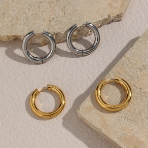 Thick hoop earrings in gold and silver stainless steel finish on stone background