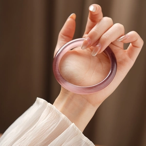 Detailed shot of purple cat eye stone bangle with smooth gradient on a woman's hand