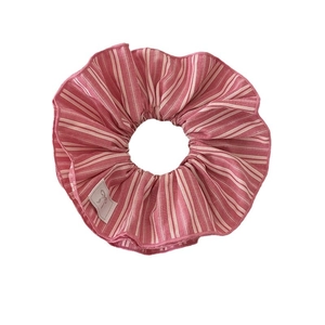 Chouchou en tissu rayé rose avec petite étiquette à nœud blanc sur fond blanc épuré