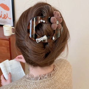 Detail of tortoise shell hair claw with plush bear and rhinestone bow on a female model