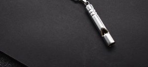 Detailed close-up of a silver metal whistle pendant with a polished finish and chain