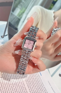 Close-up of square silver steel watch with pink shell dial and diamond markers on wrist
