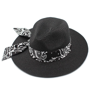 Detail of black straw Panama hat featuring a paisley ribbon bow and woven texture