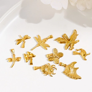 Detail of 24K gold-plated animal pendants including butterfly and dragonfly on a white plate