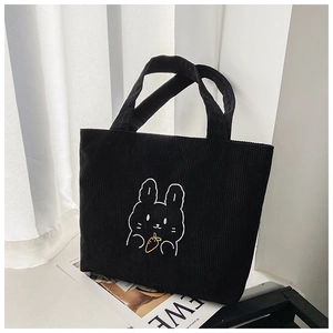 Detail of black corduroy tote bag showing cute white rabbit and orange carrot embroidery
