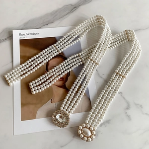 Close-up of pearl waist belts with rhinestone buckles on marble surface decoration