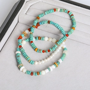 Detail of beaded bracelets with turquoise, white pearls, and red agate in a jewelry box
