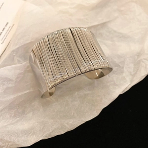 Close-up of wide silver twisted cuff bracelet with multi-layer metal wire on white art paper