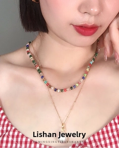 Close-up of a double-layered necklace featuring multi-colored beads and a large white pearl