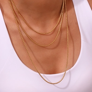Close-up of layered 18K gold plated box chains worn by a model on a white background