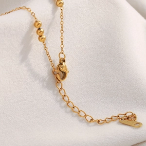 Close-up of 18K gold plated lobster clasp and bead accents on a sun pendant necklace
