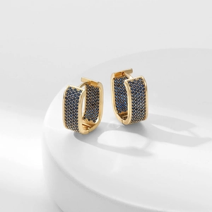 Elegante goldene U-förmige Creolen mit blauen Zirkonia auf einem weißen Podest