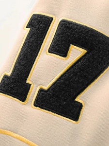 Gros plan sur la broderie bouclée du chiffre 12 sur la veste de baseball beige