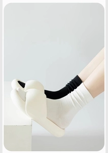 Close-up of model wearing black and white ribbed cotton socks with stylish slippers