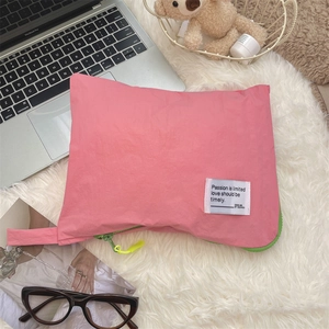 Detailed view of pink nylon waterproof organizer bag with green zipper on plush background