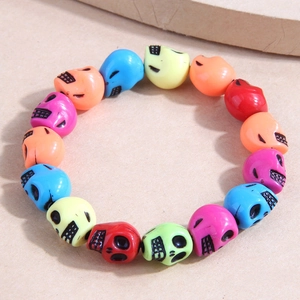 Vibrant colorful skull bead bracelet with resin skulls on a natural wood background