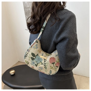 Detail of the colorful floral embroidery and golden hardware on the canvas shoulder bag