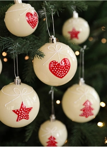 Macro shot of ivory Christmas ball ornaments with red glitter stars and hearts on a tree