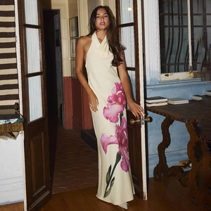 Robe dos nu beige chic avec imprimé floral iris rose sur mannequin devant une porte vintage