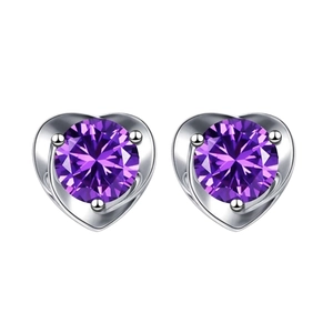 Macro detail of heart-shaped silver earrings with sparkling round purple gemstones
