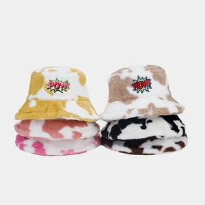 Detail of plush bucket hats with cow print patterns and colorful embroidered patches