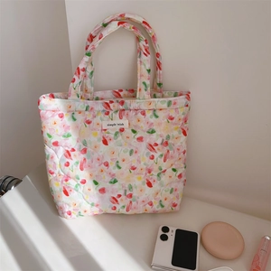 Close-up of floral quilted tote bag showing intricate red flower pattern and stitch detail