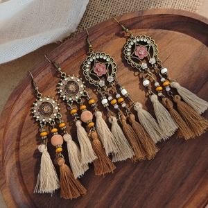 Detailed view of bohemian feather fringe earrings with woven beads and metal floral charms