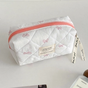 Détail de la trousse de maquillage matelassée avec nœuds roses et ruban de fermeture
