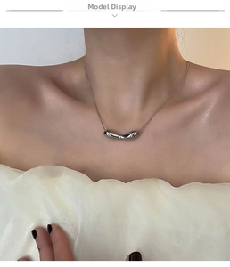 Detail shot of a silver liquid metal pendant on a delicate snake chain worn on the neck