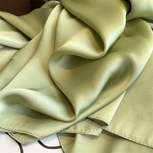 Close-up of green satin scarf fabric showing smooth texture and elegant silky luster