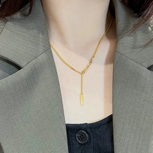 Minimalist 18K gold plated titanium lucky bar pendant necklace worn on a classic blazer