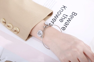Close-up of steel wire bracelet with Love You Grandma pendant and heart charm on wrist
