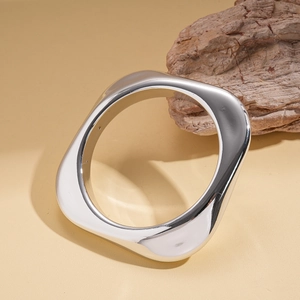 Macro shot of silver irregular geometric bangle with a high-polish mirror finish on wood