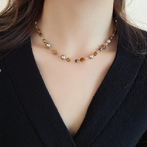 Detail einer Perlenkette aus Tigerauge und Muschelperlen, getragen am Model, elegant