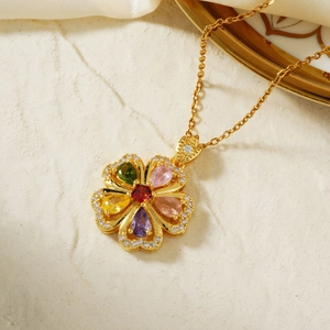 Elegant gold flower necklace with colorful zircon gemstones on a white stone background