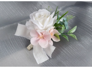 Close-up of white rose wedding boutonniere with silk ribbon on grey satin background