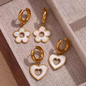 Macro view of gold-plated 18K flower and heart drop earrings with white shell inlay