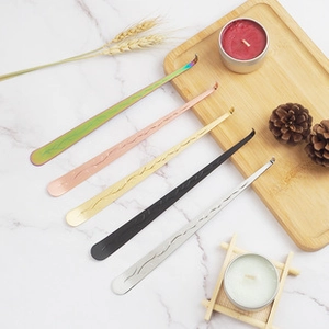 Set of five multi-colored metal candle wick hooks on a decorative marble surface