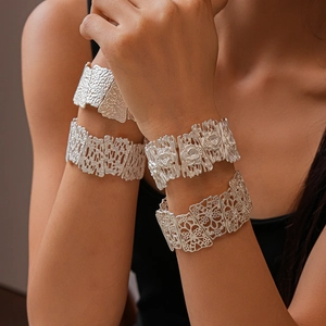 Macro detail of silver wide bracelets with matte floral patterns and irregular hollow textures
